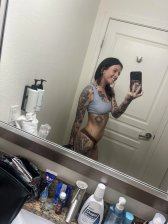 Cute young woman smiling shyly while stripping clothes off in bedroom