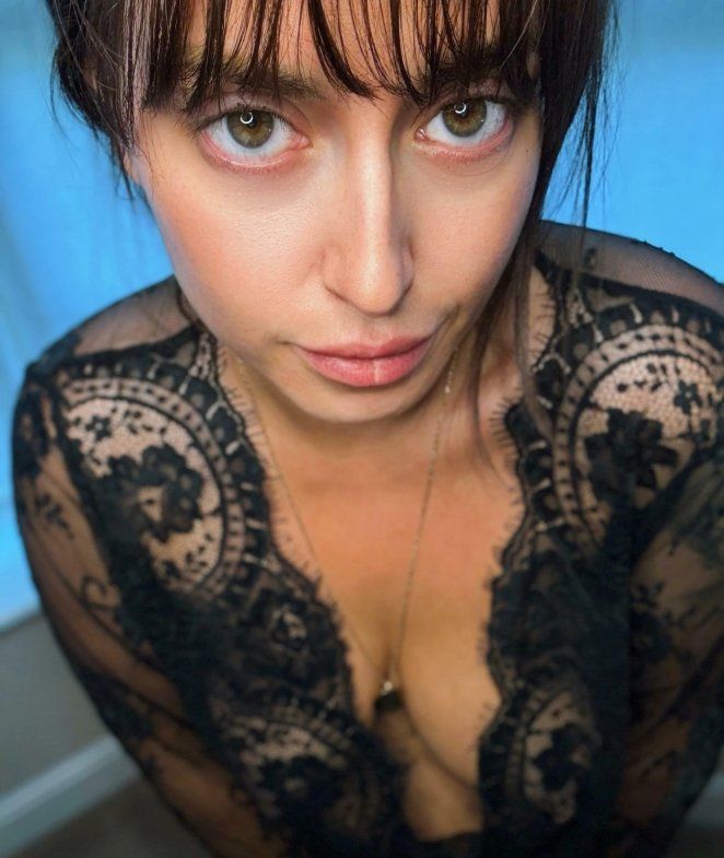 Woman leaning forward showing cleavage with a playful direct gaze