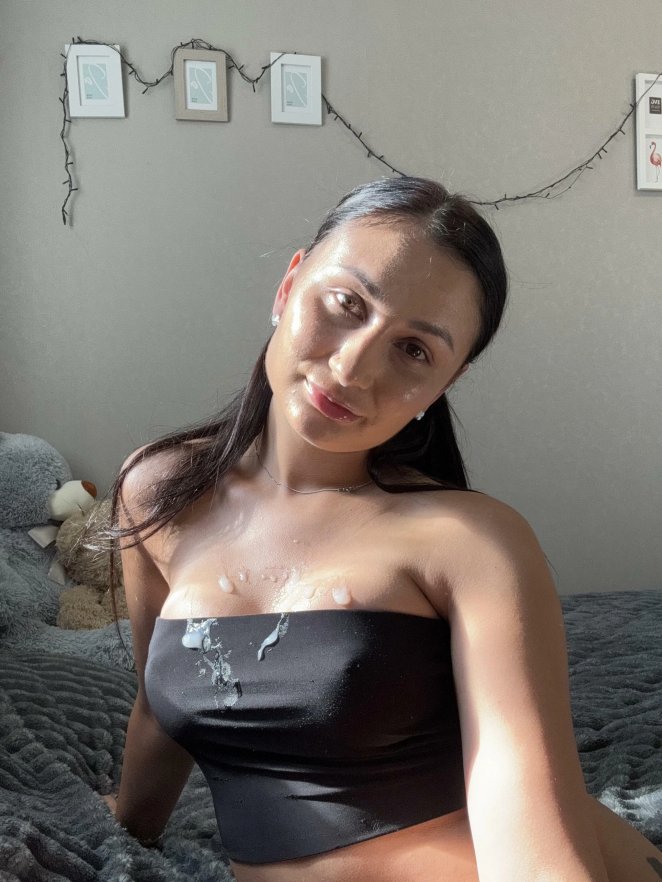 Cute person smiling and posing fully clothed, hinting at more beneath