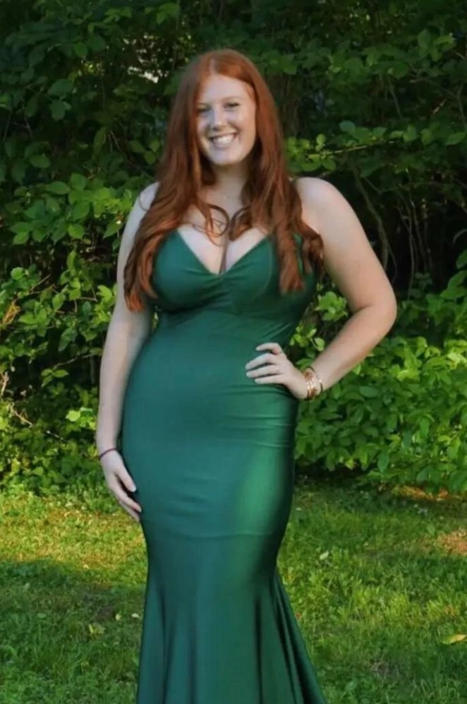 Redhead woman posing in a form-fitting green dress, looking confident