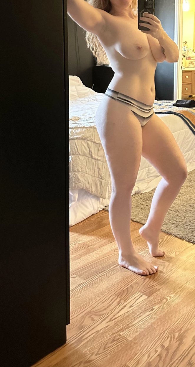 Curvy woman posing nude in front of a large new mirror