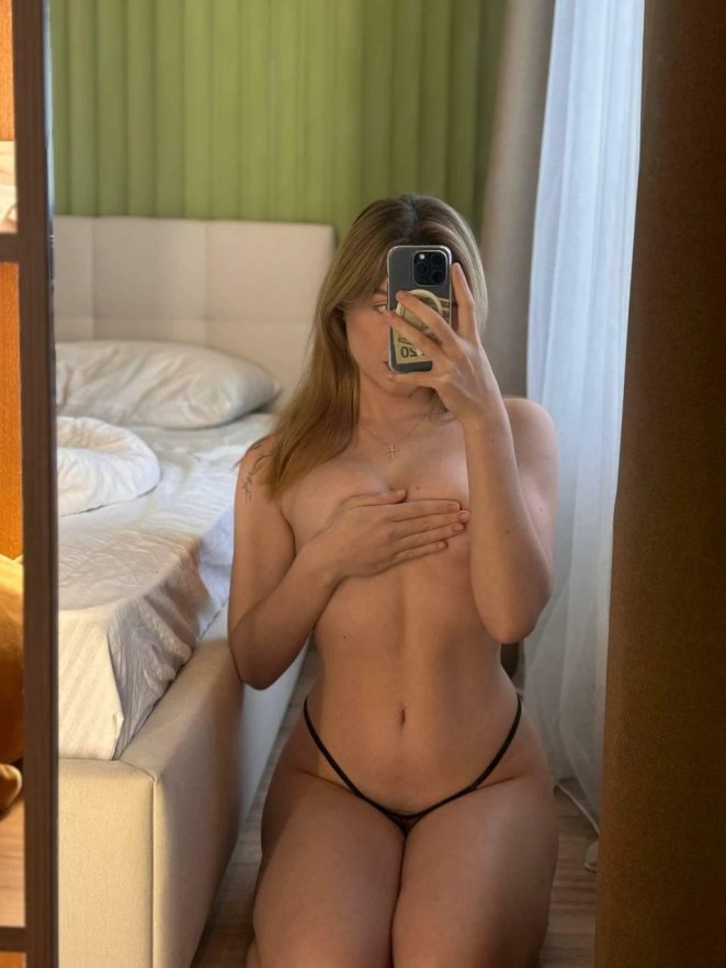 Petite woman nestled playfully among soft pillows on a bed