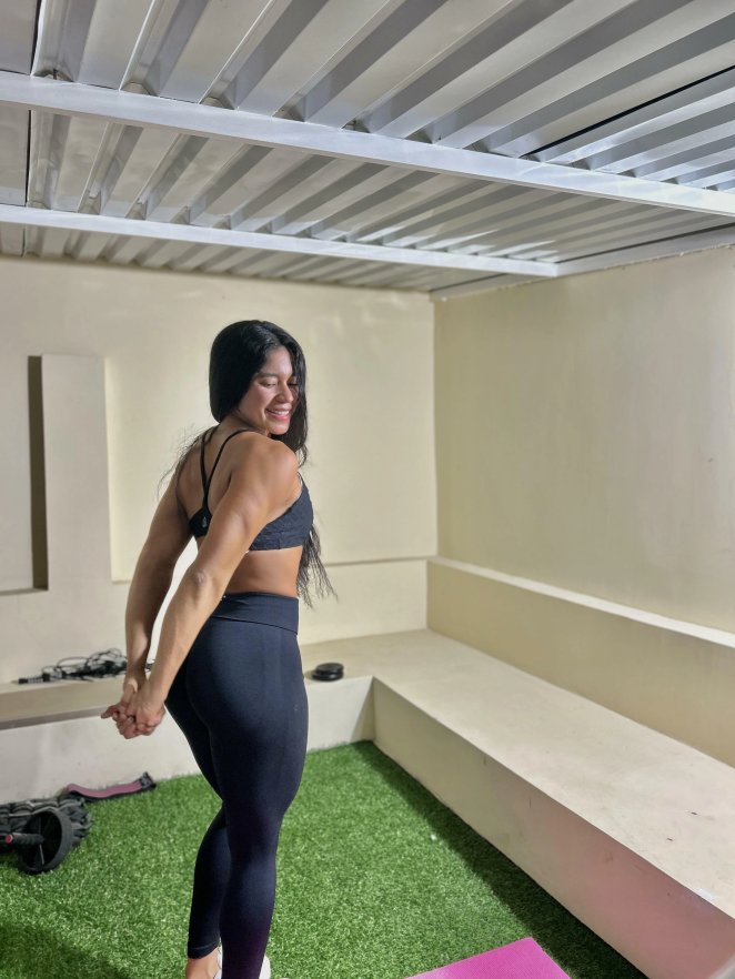 Fit adult woman in yoga pants with long dark hair poses confidently