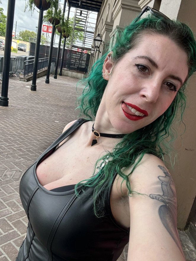 Woman in leather top showing deep cleavage, looking at camera