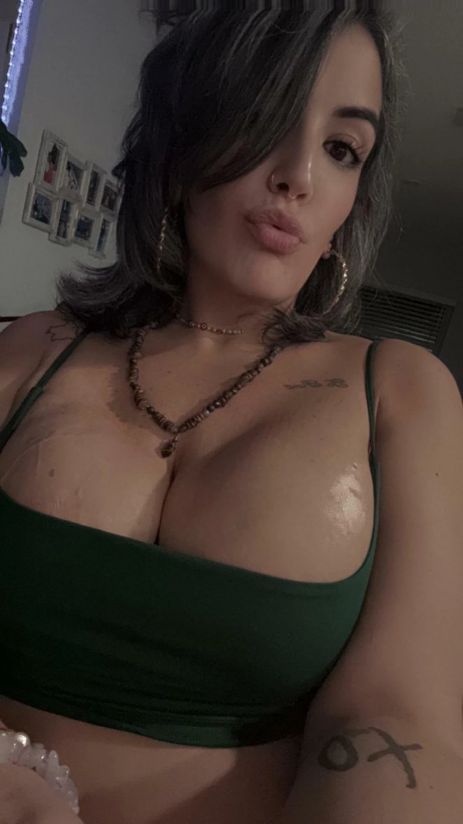 Latina woman posing seductively in dim evening lighting, looking at camera