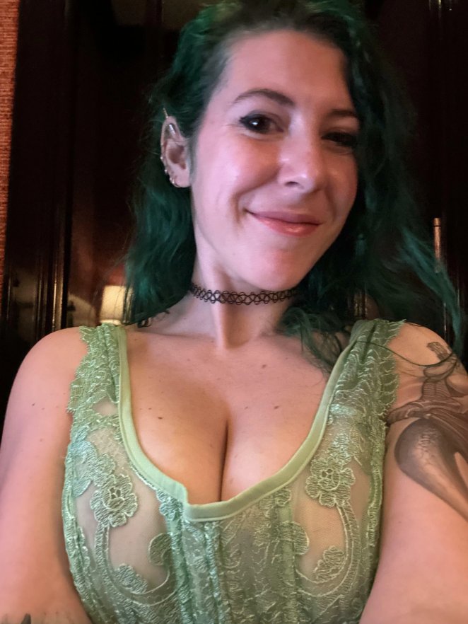 Woman in green lace top showing off her décolletage and cleavage