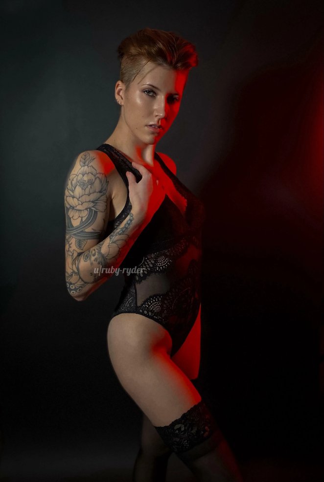 Naked redhead woman posing dramatically while wielding a red lightsaber