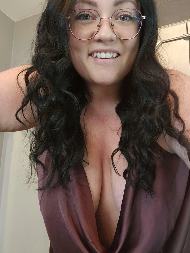 Woman confidently displaying deep cleavage while inviting viewers to look and enjoy.