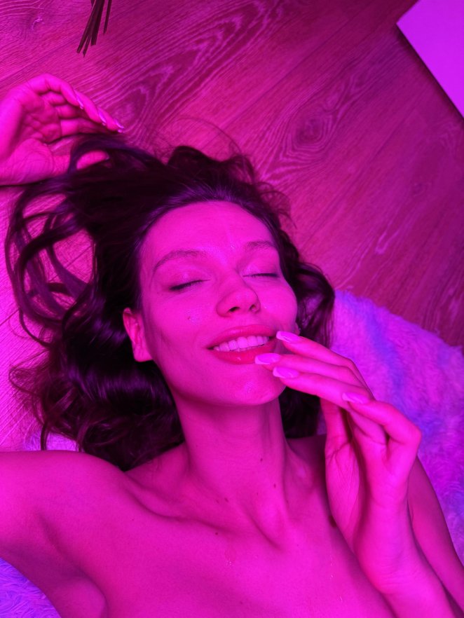 Smiling young woman with semen on her face looking at camera